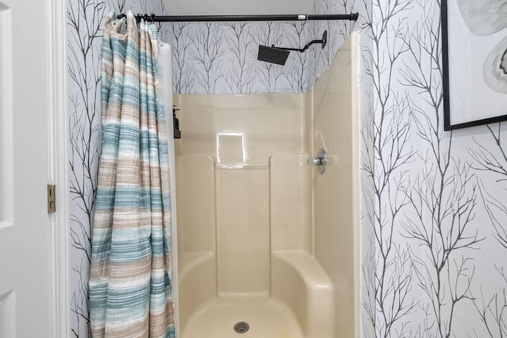 Stylish shower with rainfall head and elegant tree-pattern wallpaper