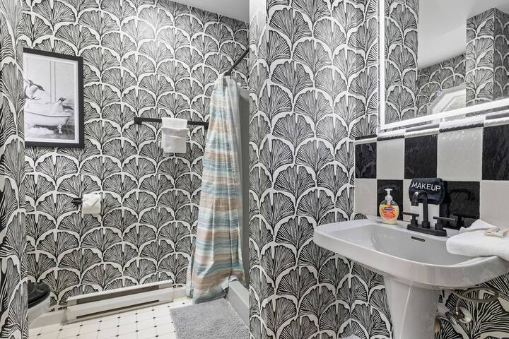Bold designer bathroom with stylish wallpaper and shower-tub combo