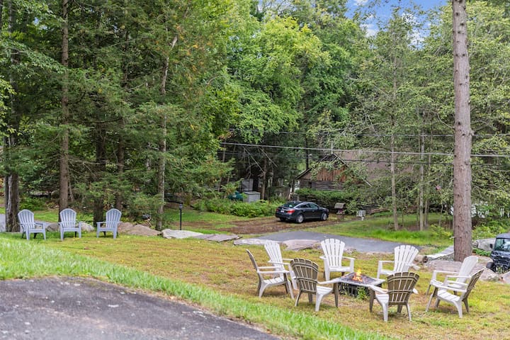 Wooded lawn with Adirondack seating and a cozy outdoor fire pit