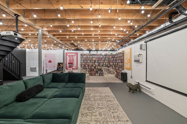 Spacious lounge with projector, library wall, and cozy sectional seating