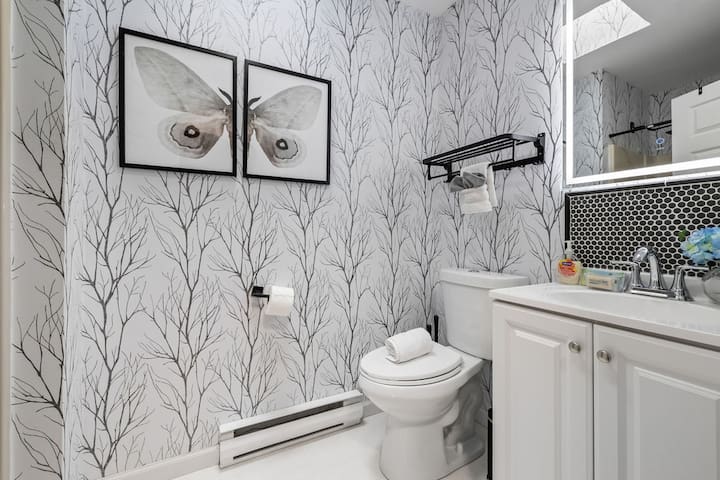Stylish full bath with designer wallpaper and bright, modern finishes