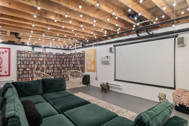 Cozy media lounge with projector, library wall, and ambient string lights