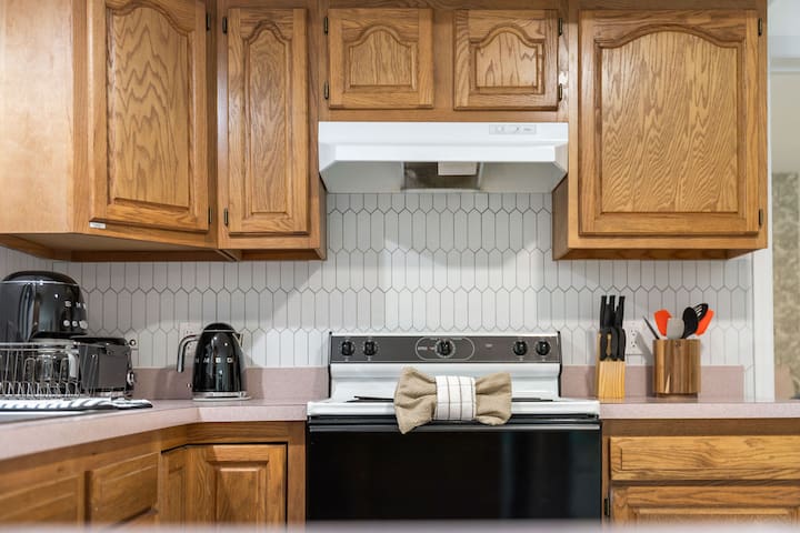 Warm wood kitchen with full cooking setup and stylish tile backsplash