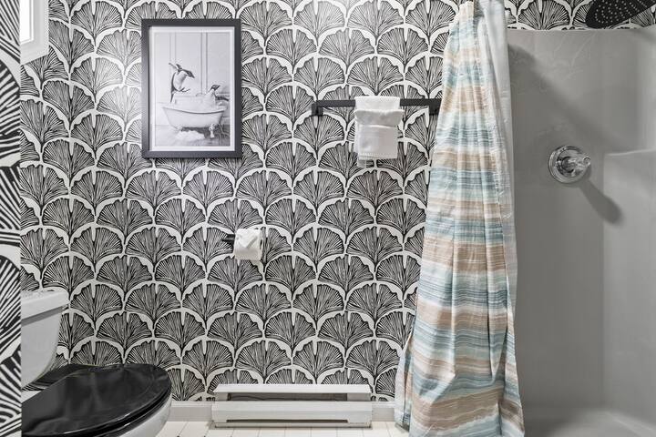 Stylish bathroom with bold wallpaper and tub-shower combo