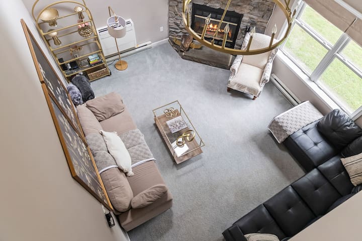 Bright two-story living room with stone fireplace and stylish seating