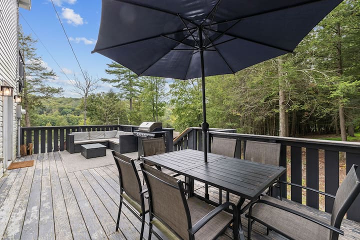 Private wooded deck with outdoor dining, lounge seating, and grill