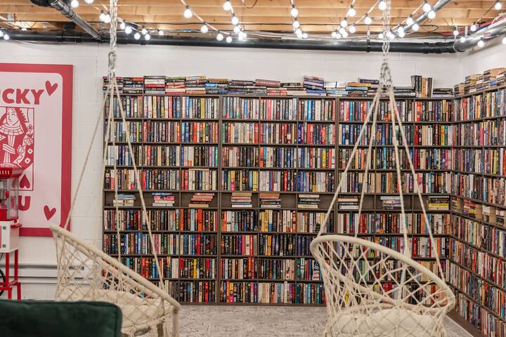 Cozy library lounge with hanging chairs and floor-to-ceiling bookshelves