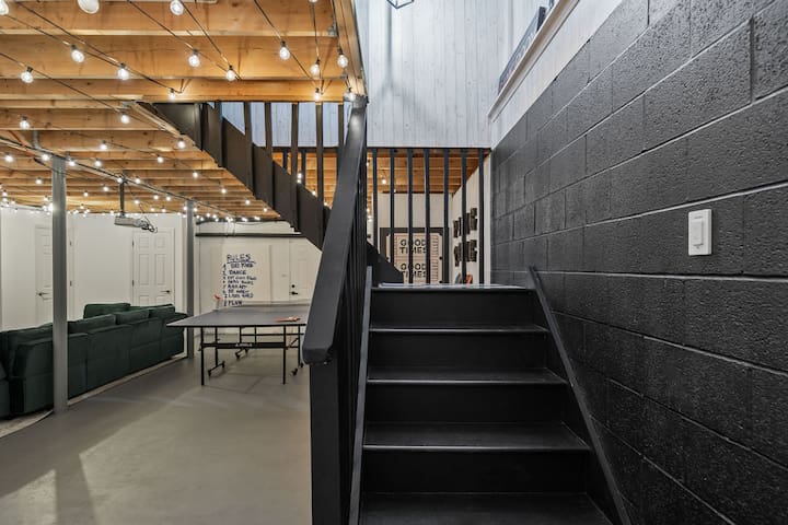 Industrial-chic game room with ping pong, lounge seating, and warm string lights