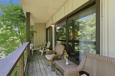Private covered balcony with cozy seating and tranquil tree views