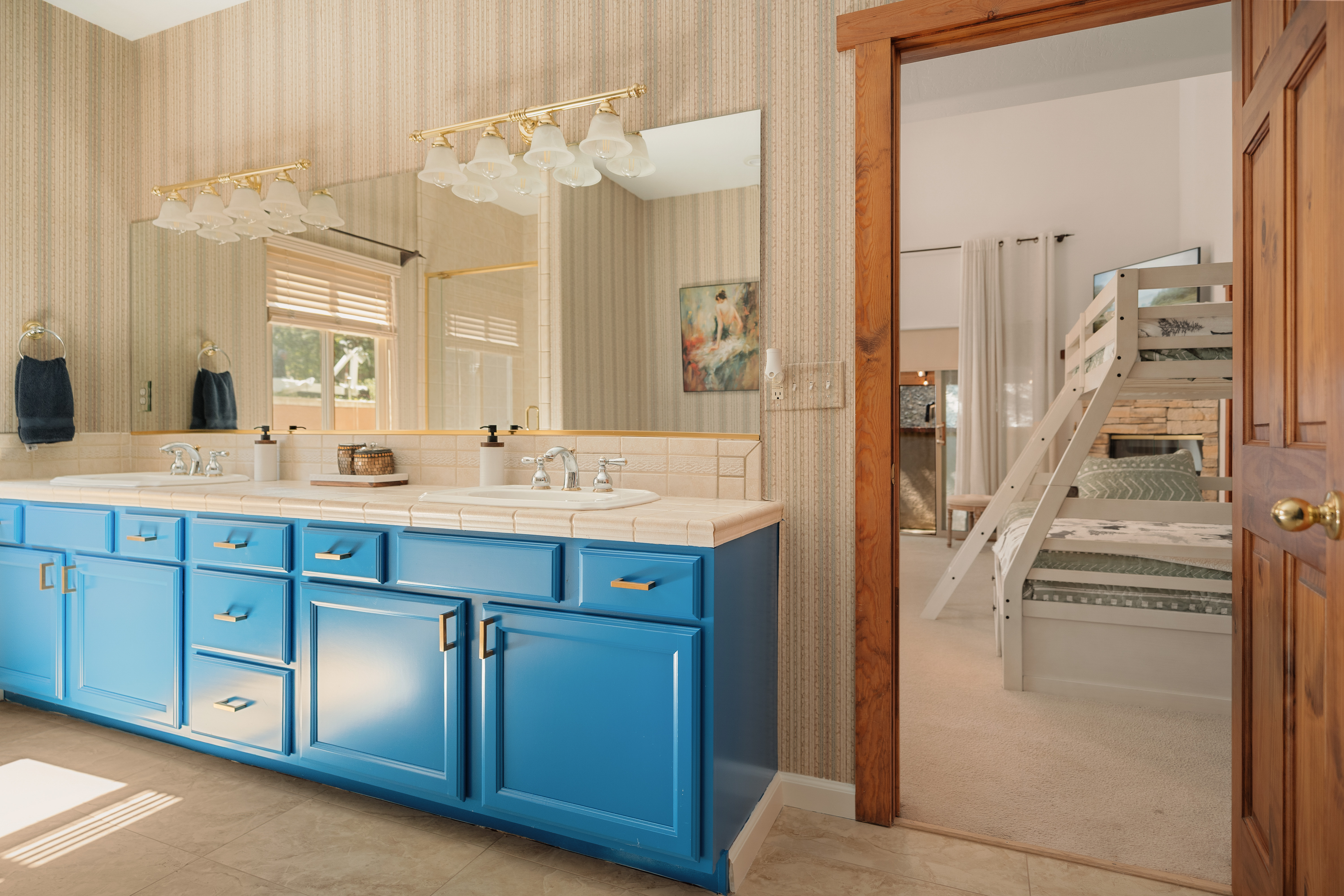 Spacious double-vanity bath with bold blue cabinets and family-friendly bunk room