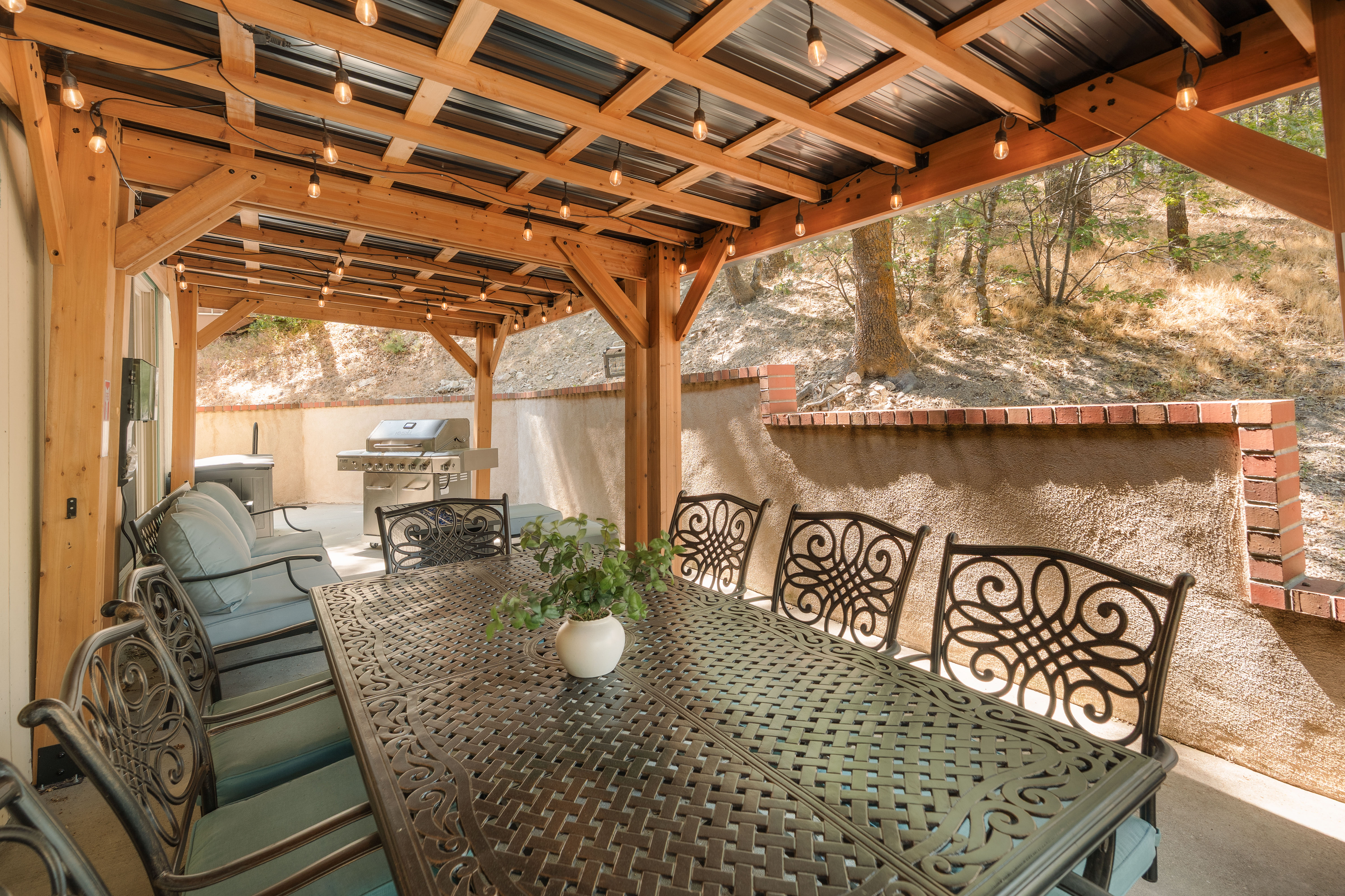 Covered patio with string lights, outdoor dining, and built-in grill