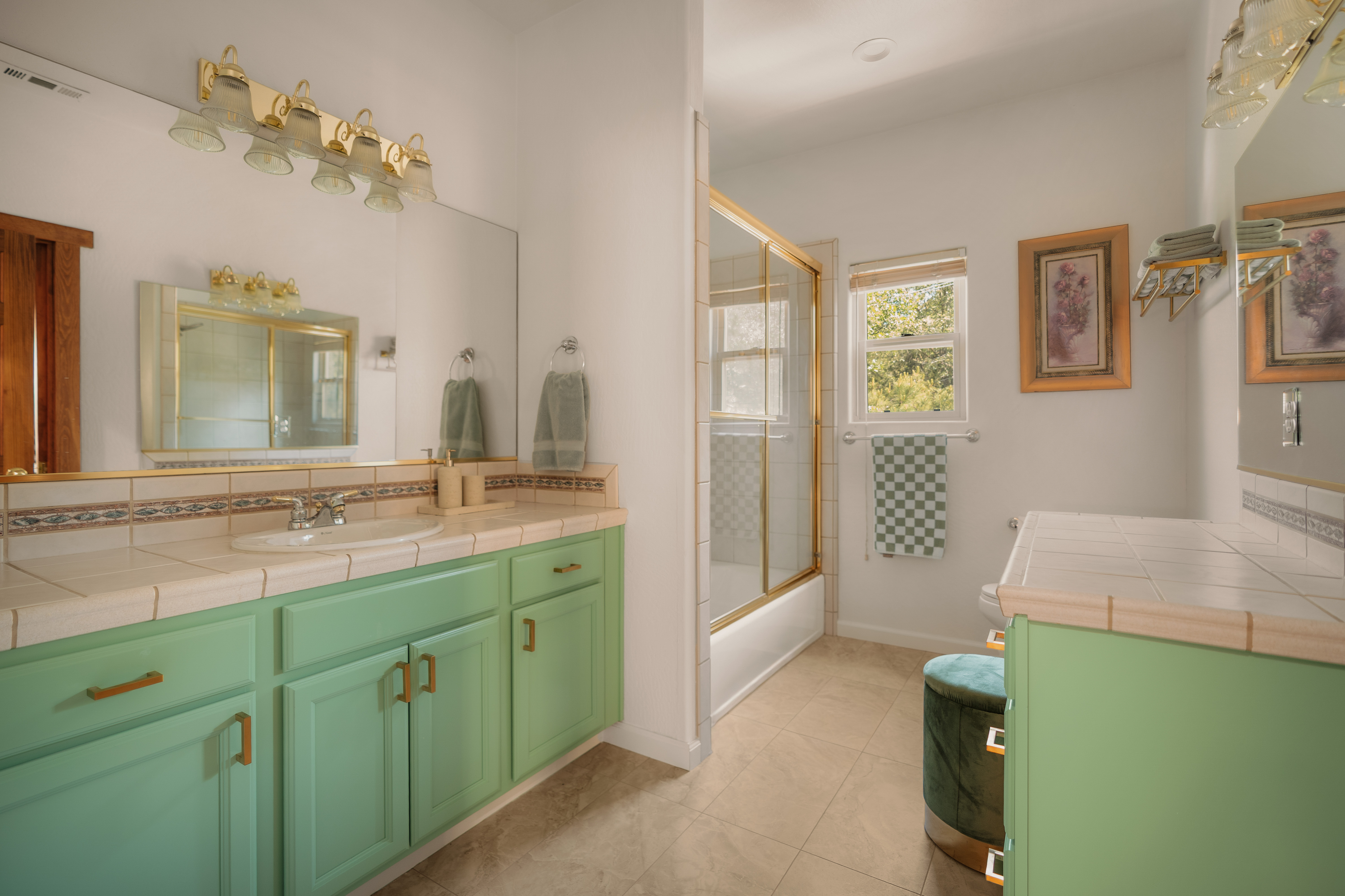 Bright bathroom with spacious vanity, natural light, and glass-enclosed tub