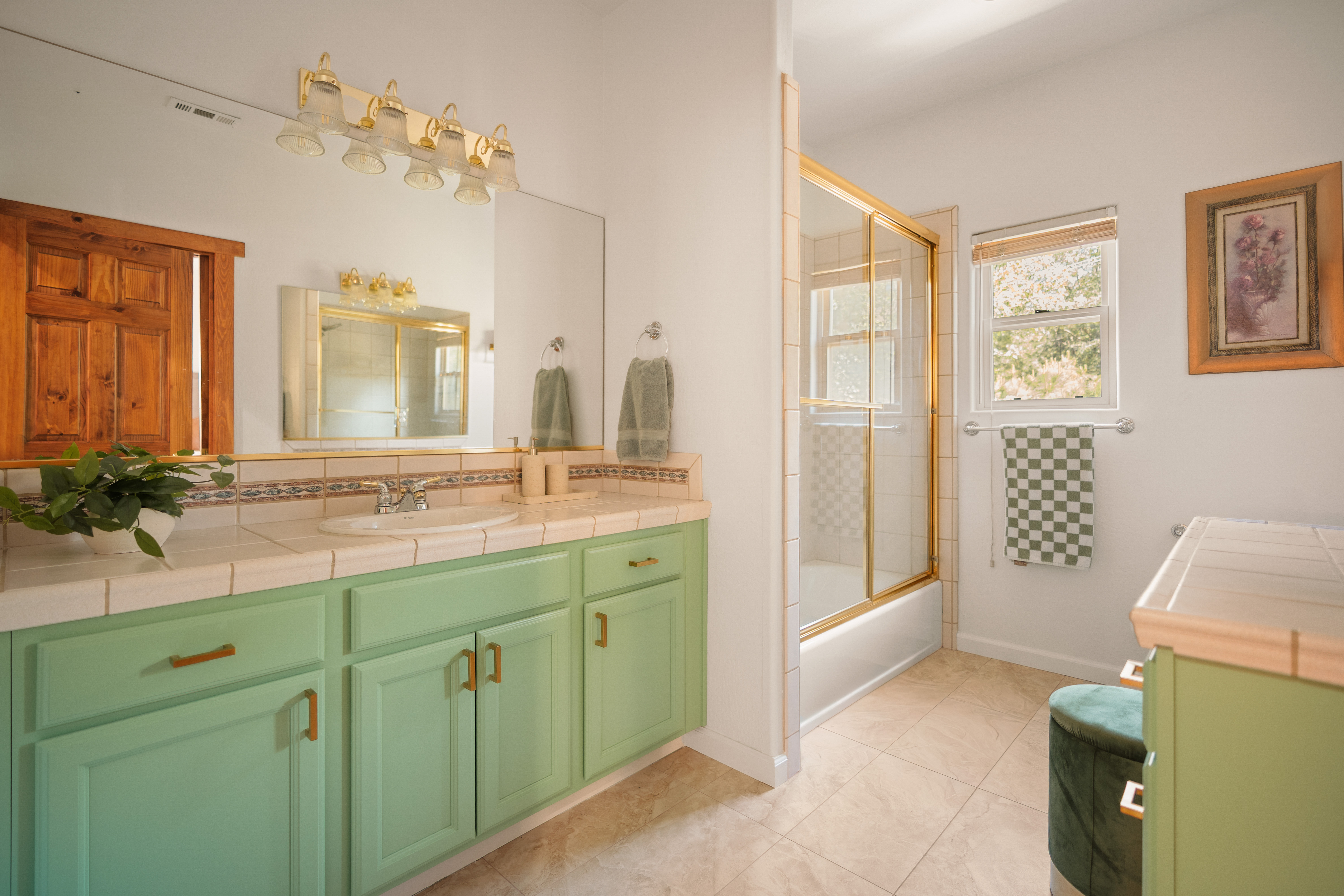 Bright bathroom with mint vanity, glass shower, and natural light