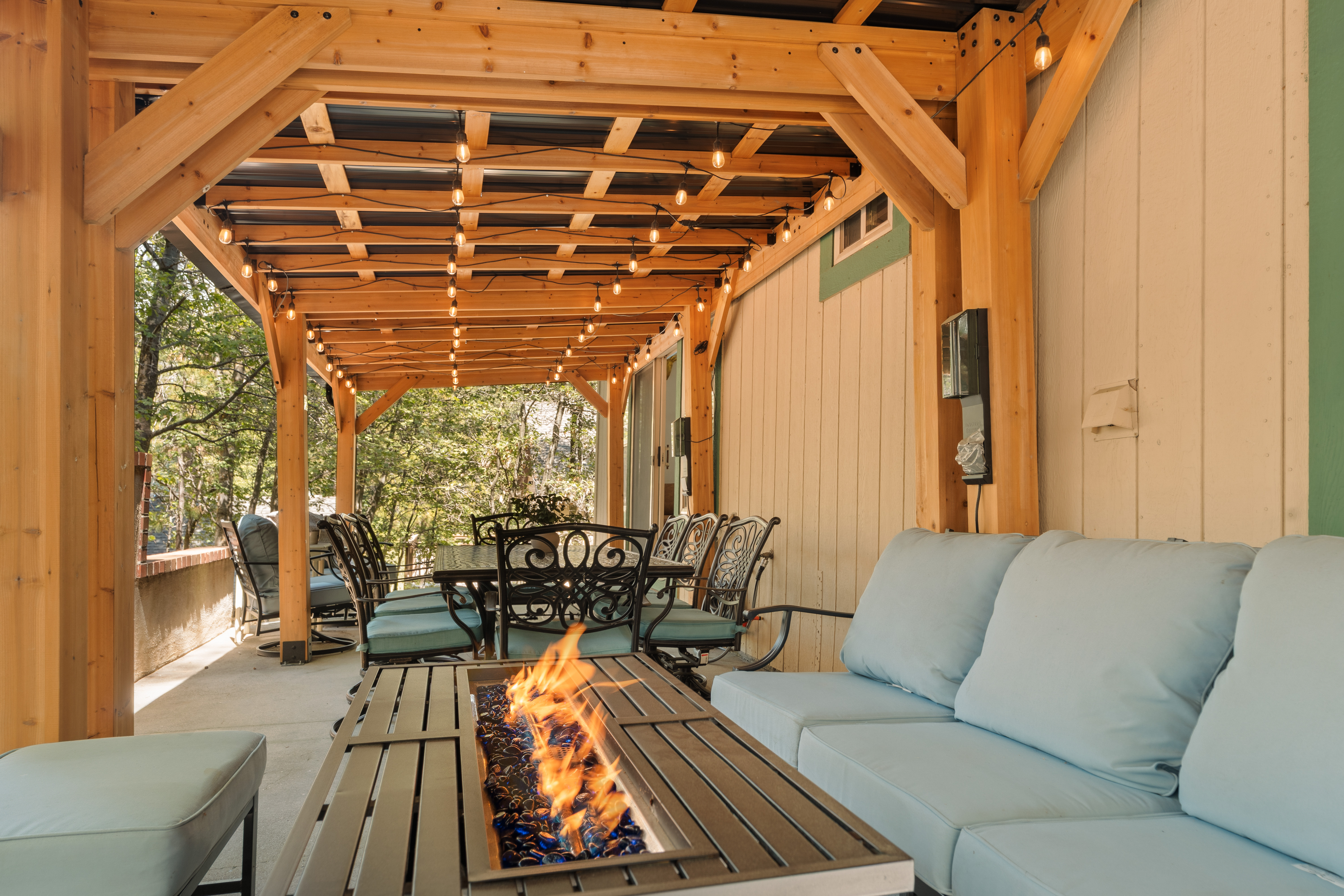 Covered patio with string lights, fire table, and inviting outdoor seating