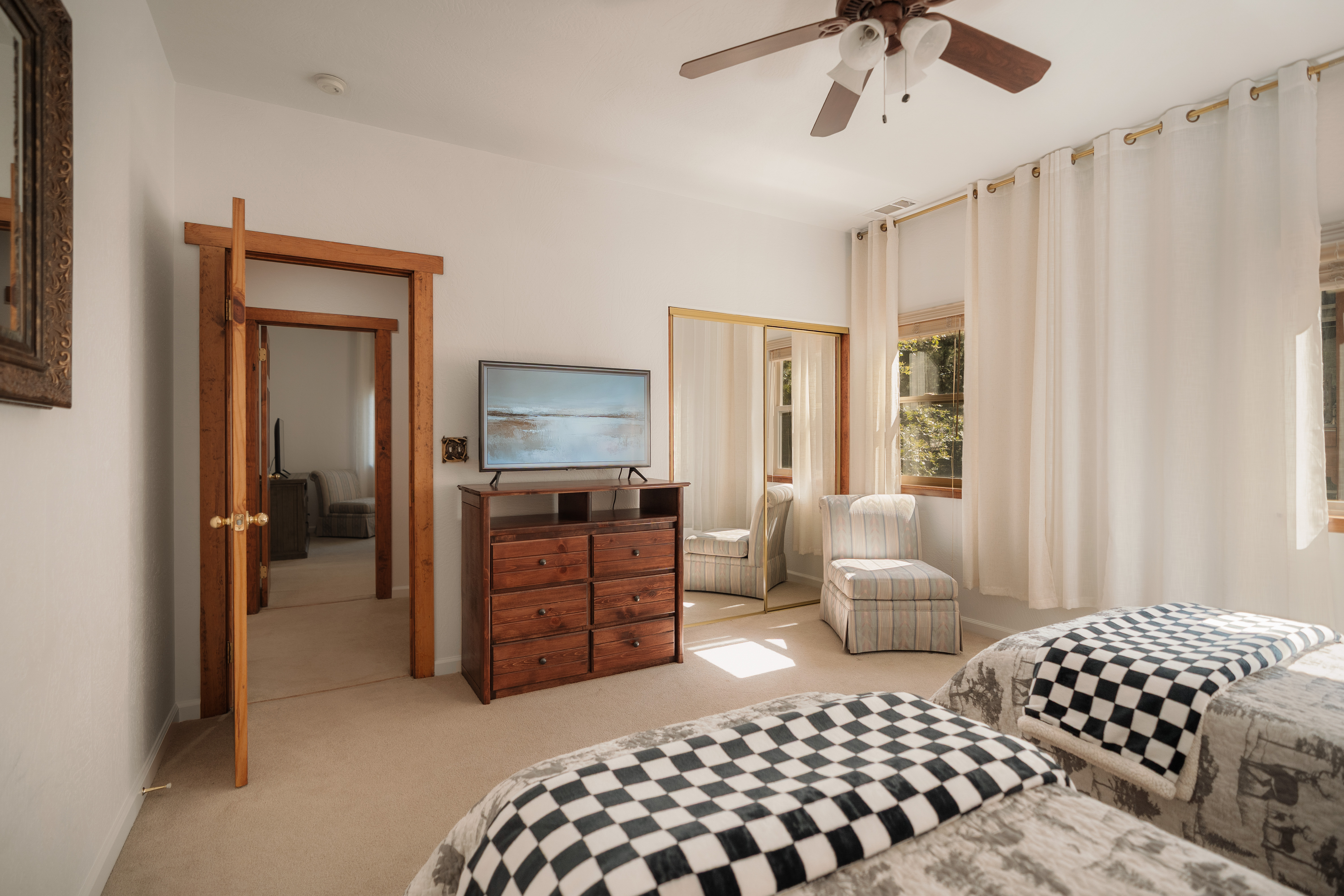 Sunny twin bedroom with TV, large windows, and a cozy reading nook