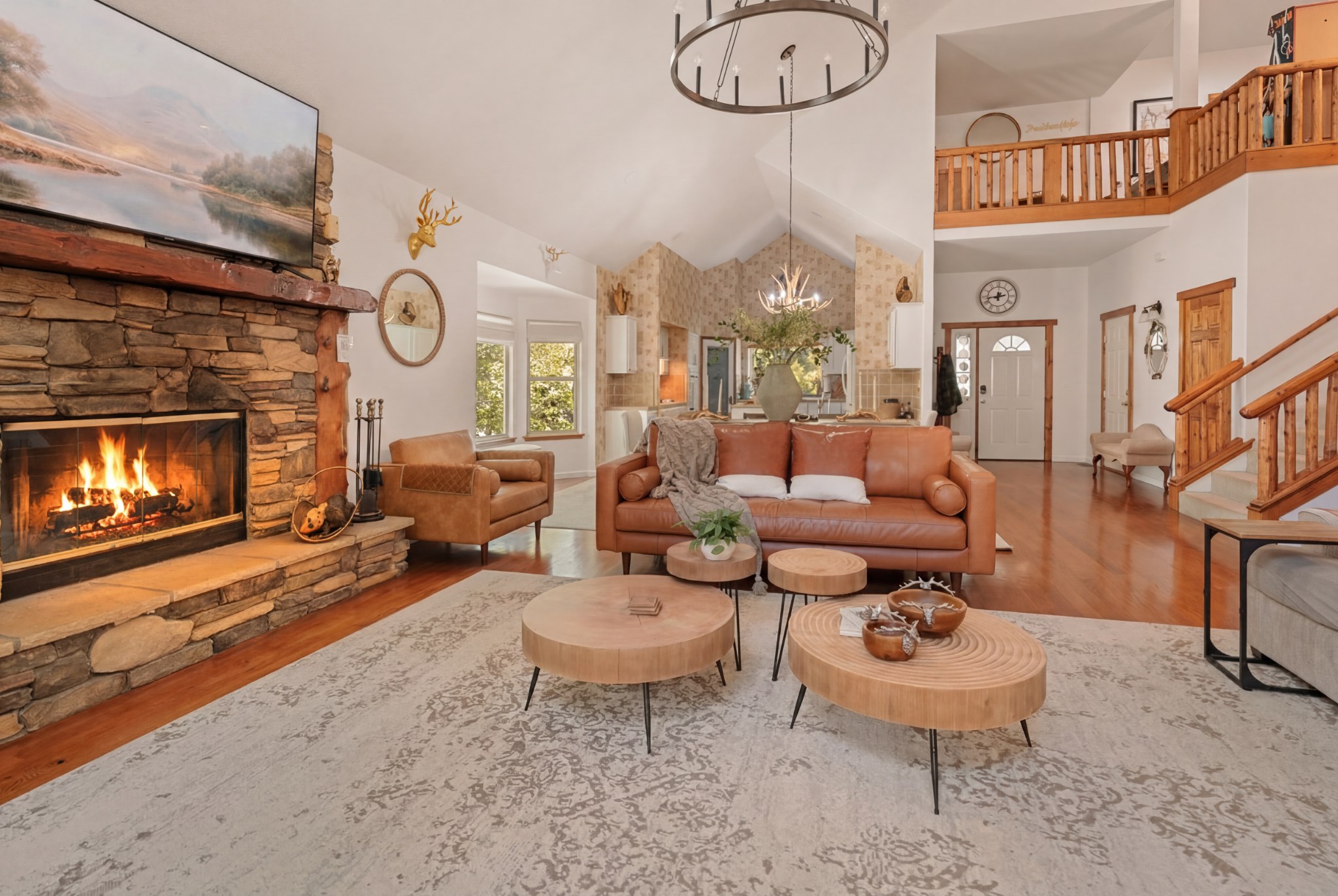 Cozy great room with vaulted ceilings, stone fireplace, and loft views