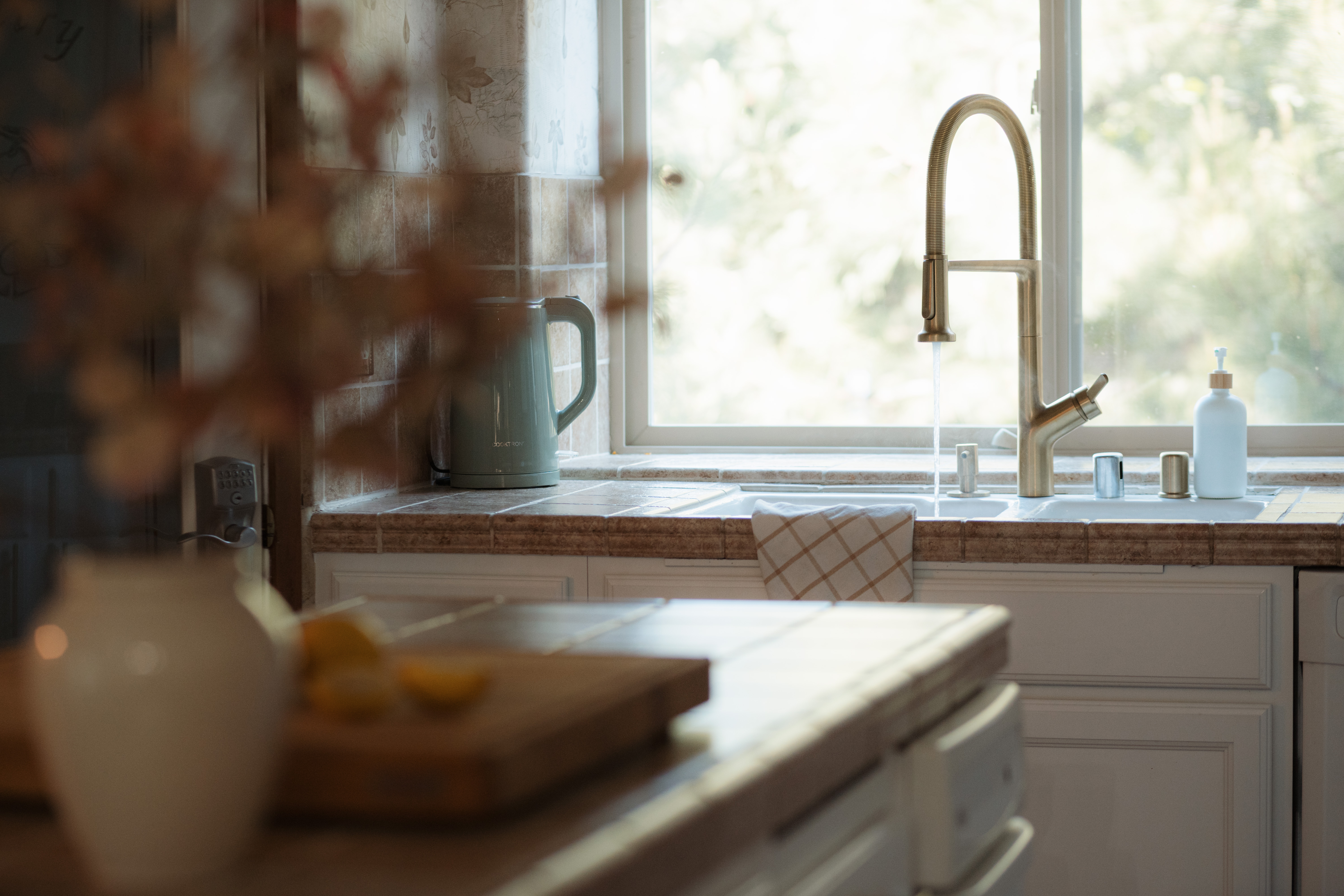 Sunlit kitchen with elegant brass faucet and serene window view