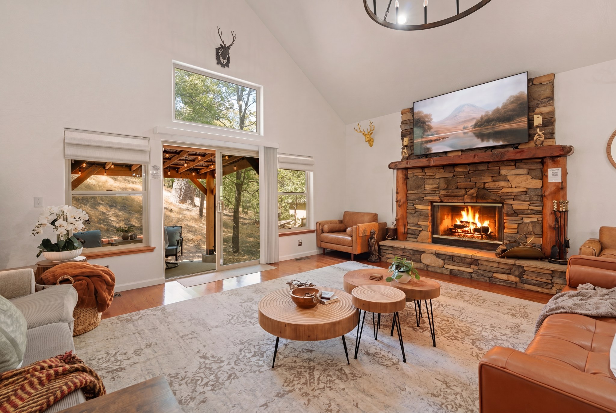 Cozy great room with stone fireplace, vaulted ceilings, and wooded views