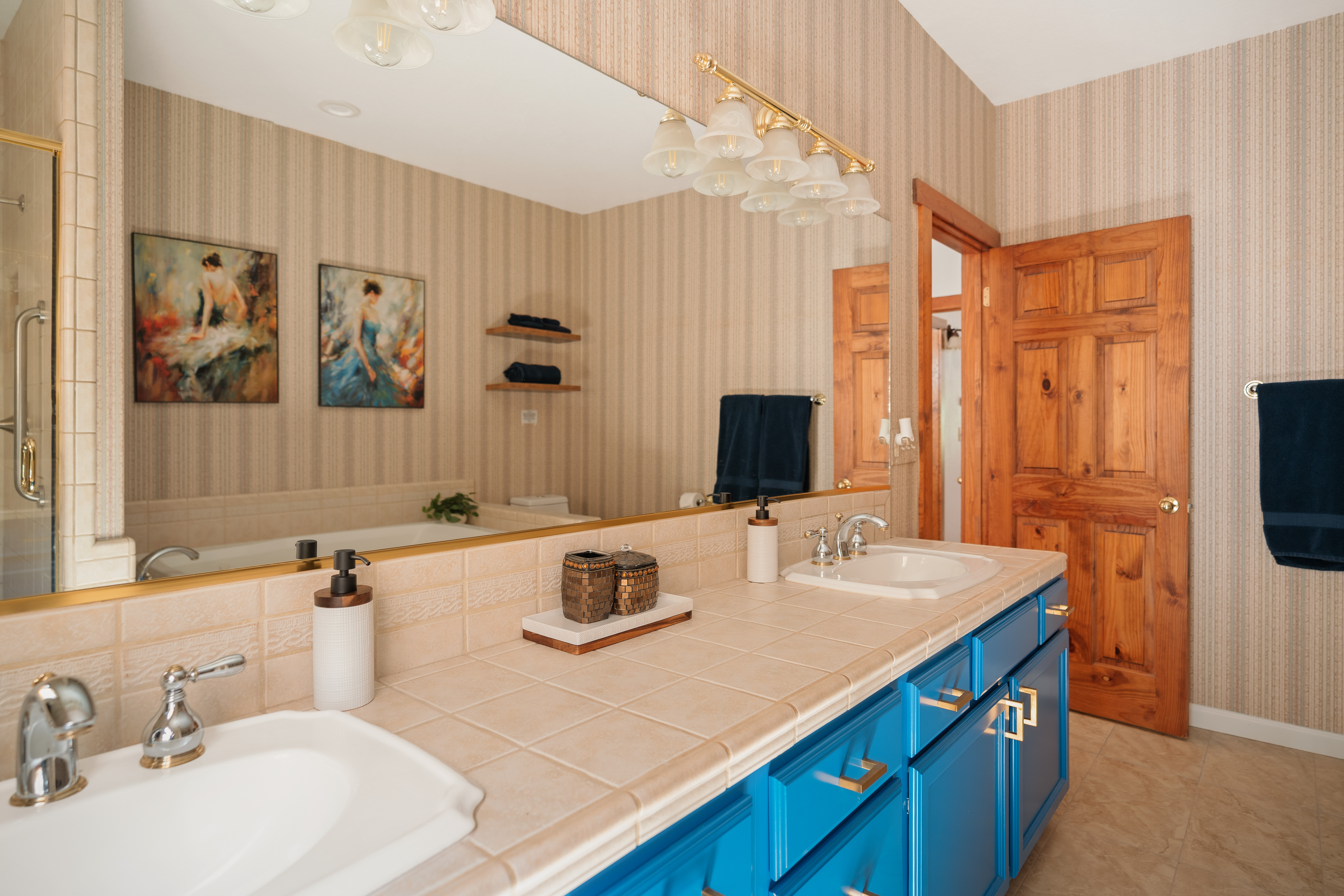 Bright double-vanity bathroom with bold blue cabinetry and warm wood accents