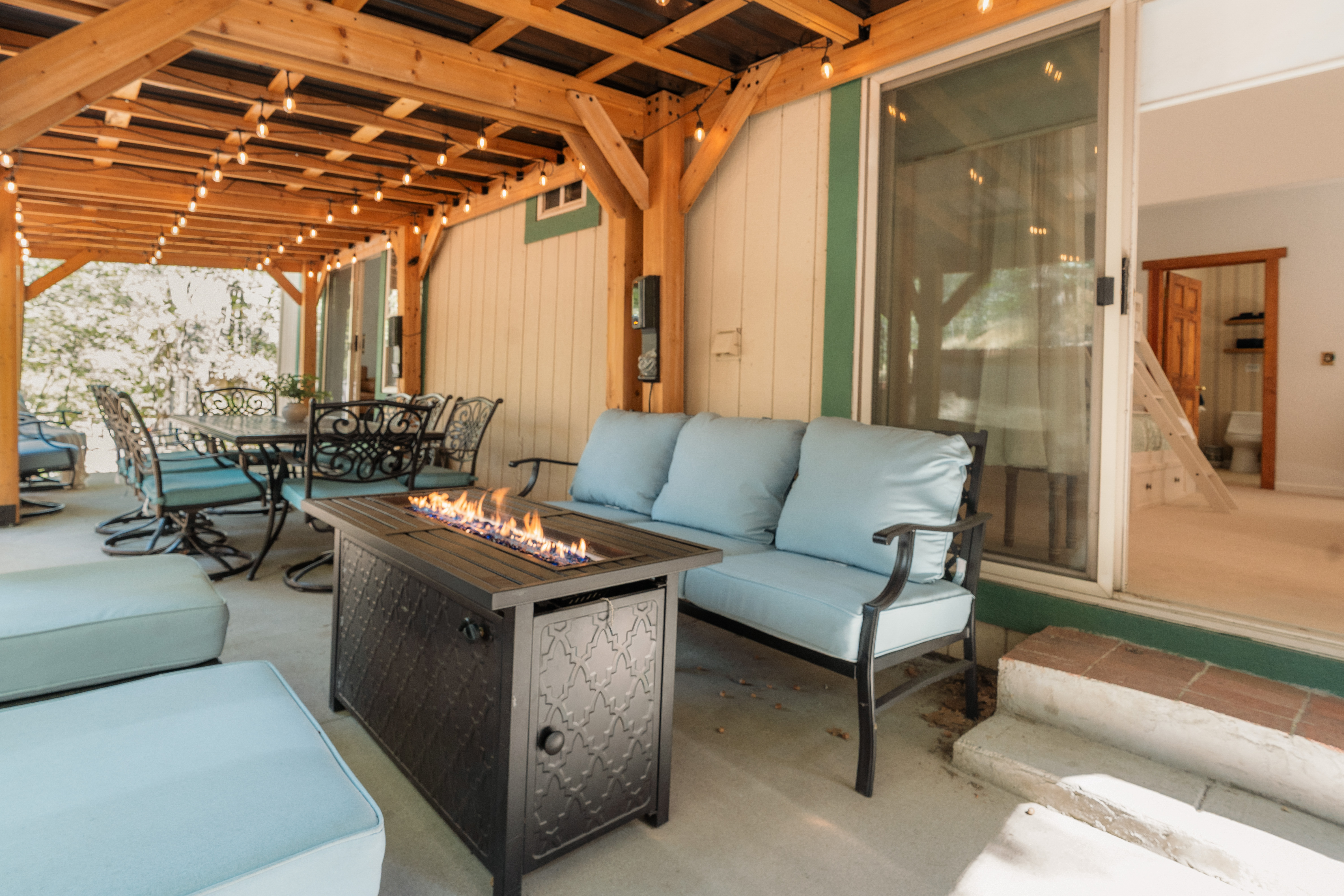 Covered patio with fire table, string lights, and inviting outdoor dining