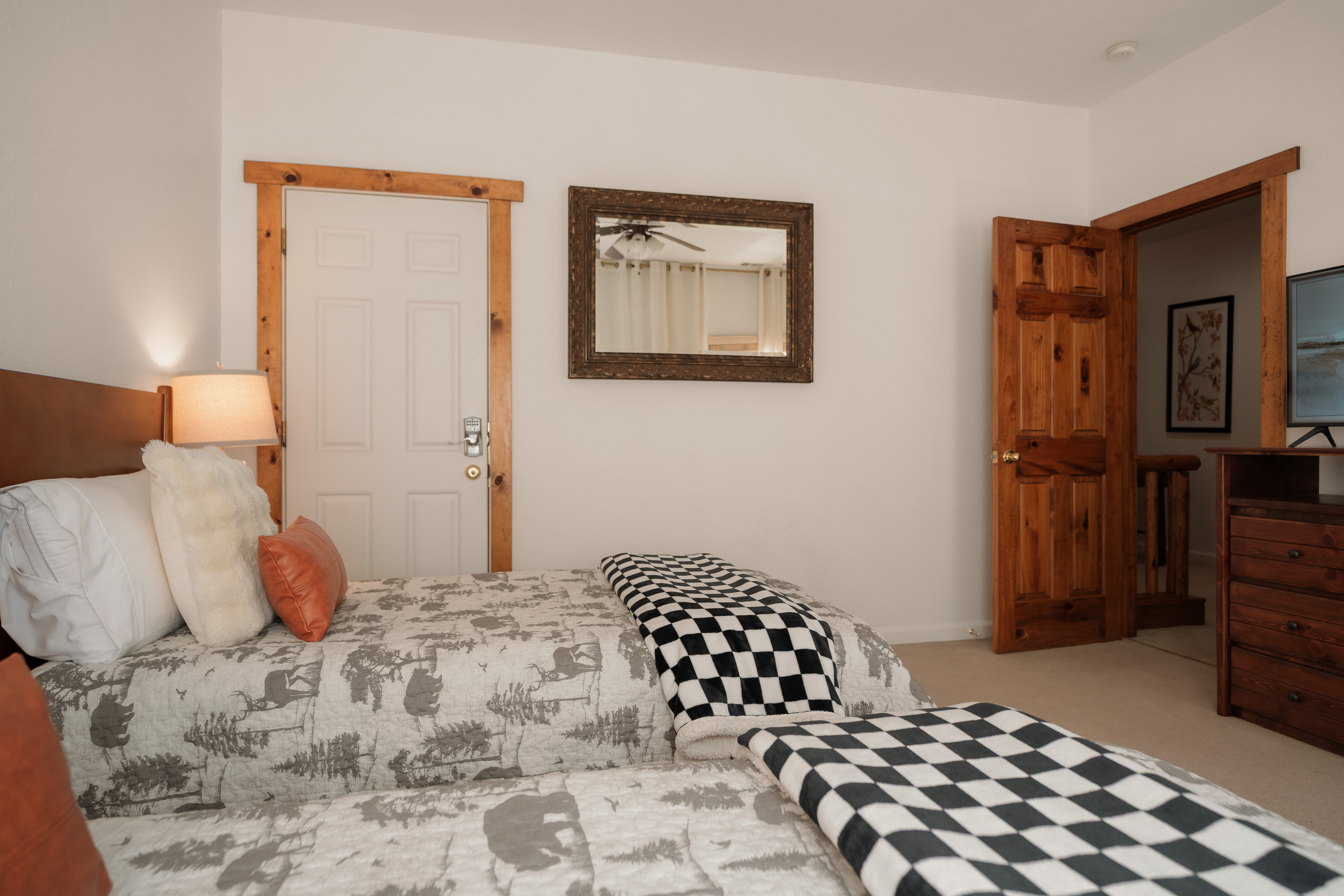 Cozy rustic bedroom with two comfy beds, warm wood accents, and TV