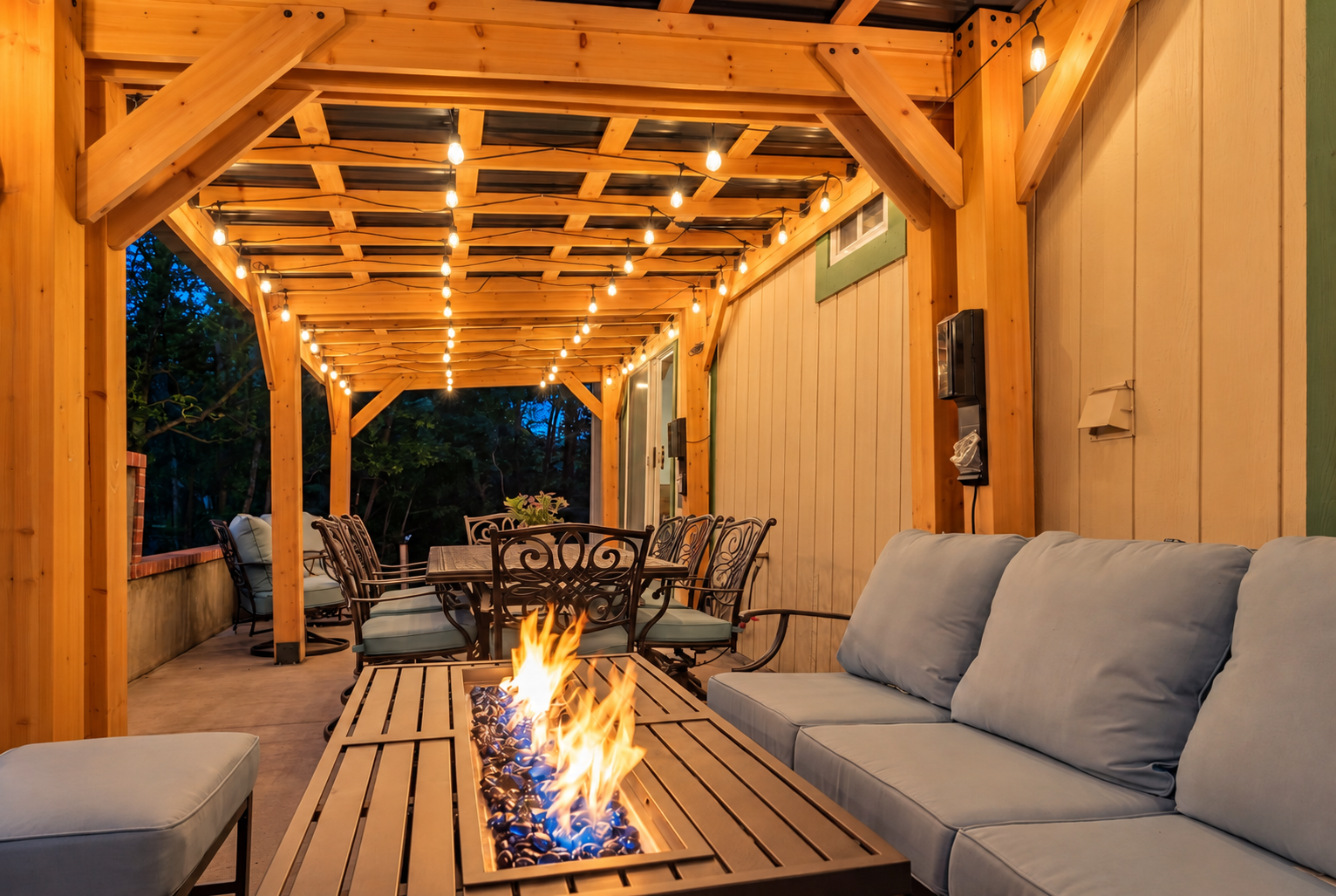Cozy covered patio with string lights, fire table, and outdoor dining