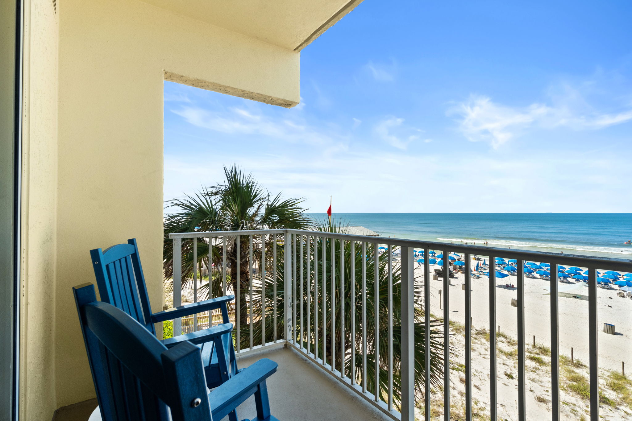 Private oceanfront balcony with rocking chairs and sweeping beach views