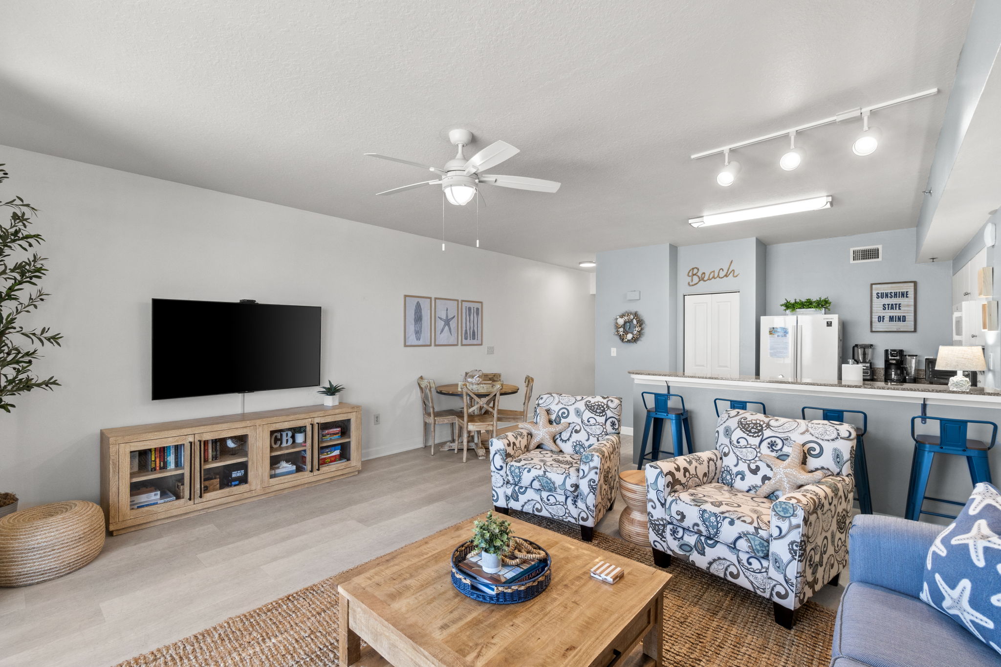 Bright coastal living room with TV and breakfast bar