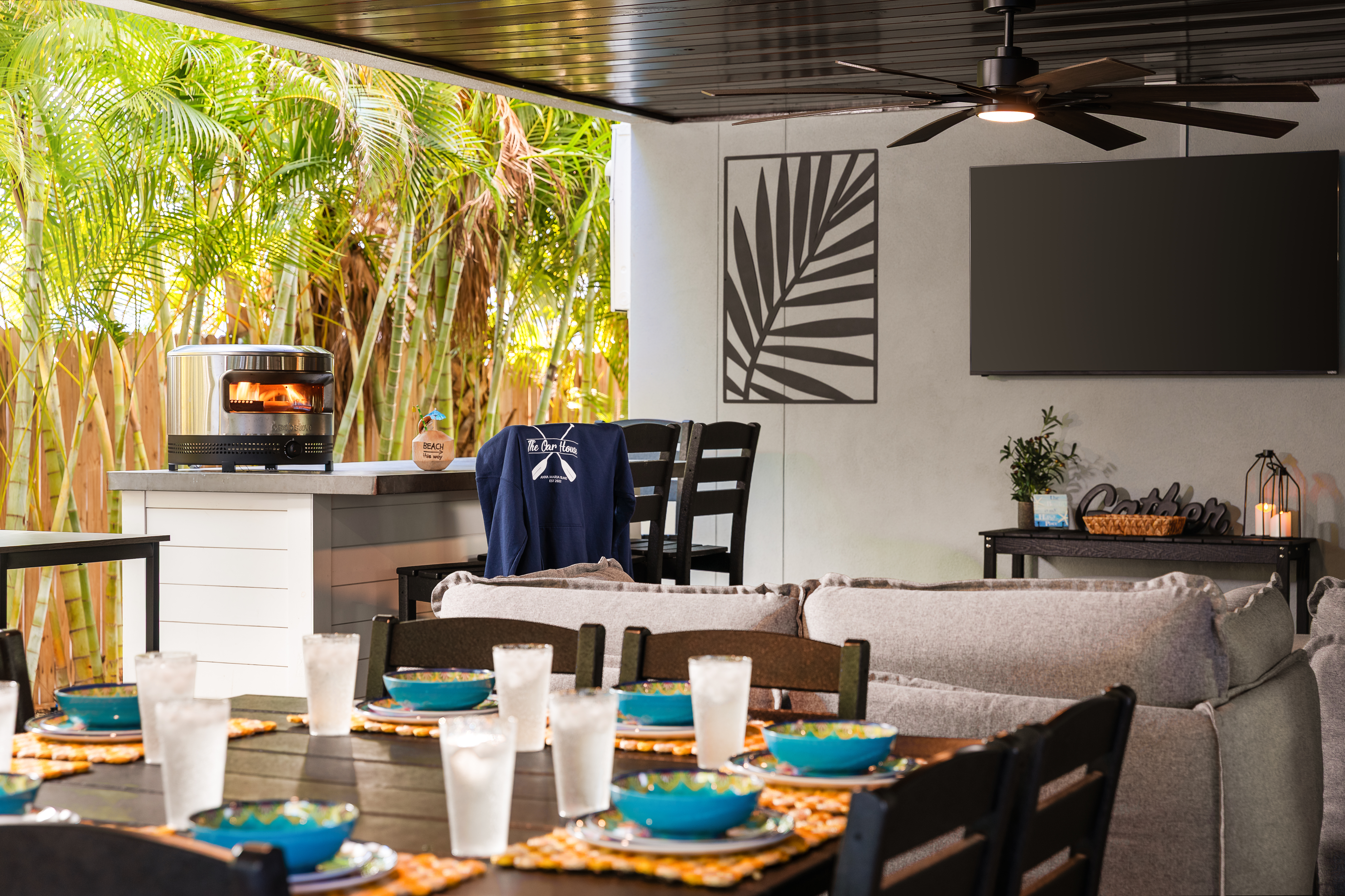 Outdoor kitchen with grill, pizza oven, dining for eight and a mounted outdoor TV