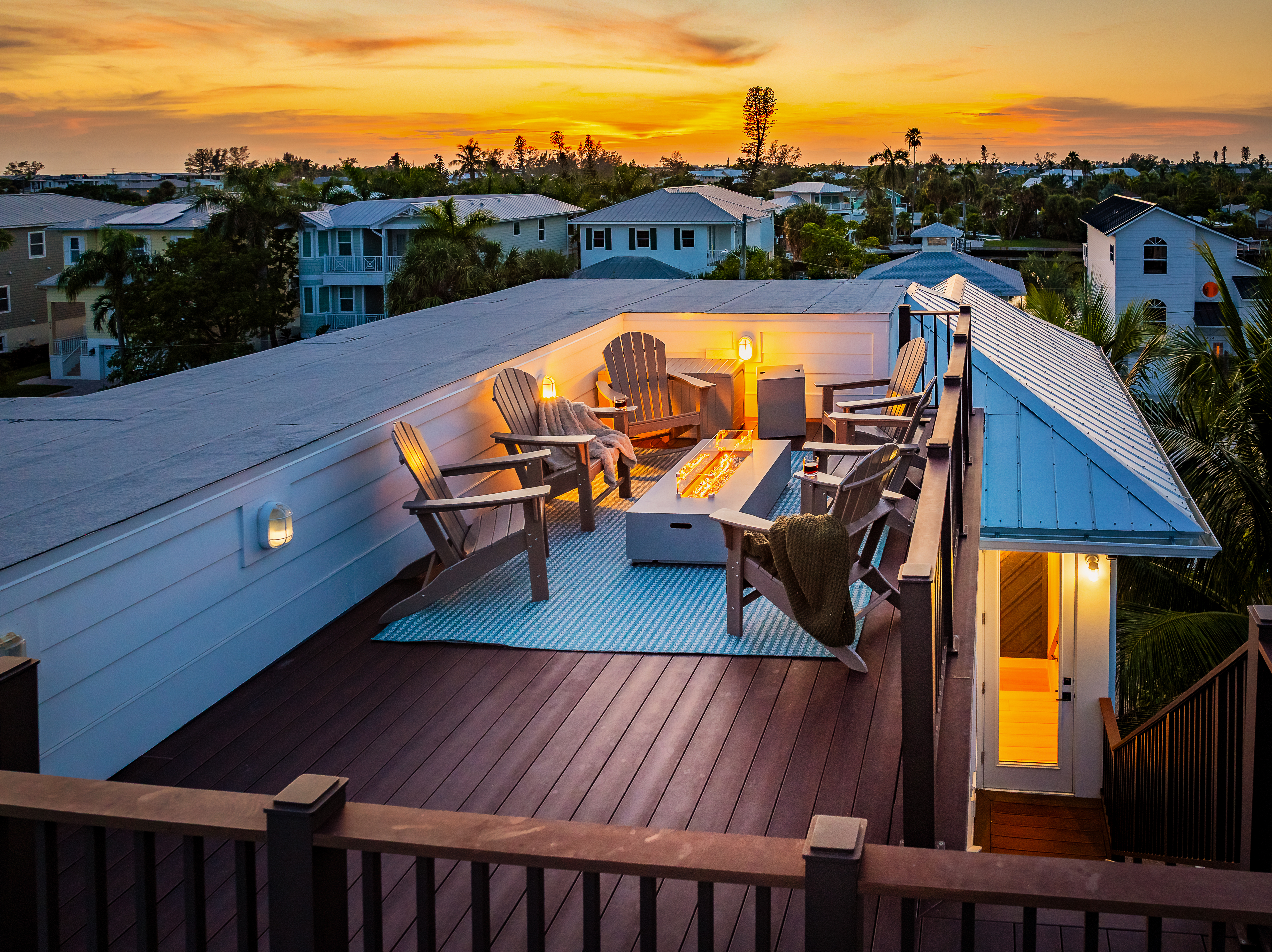Rooftop deck with Adirondack seating around a fire table and island views