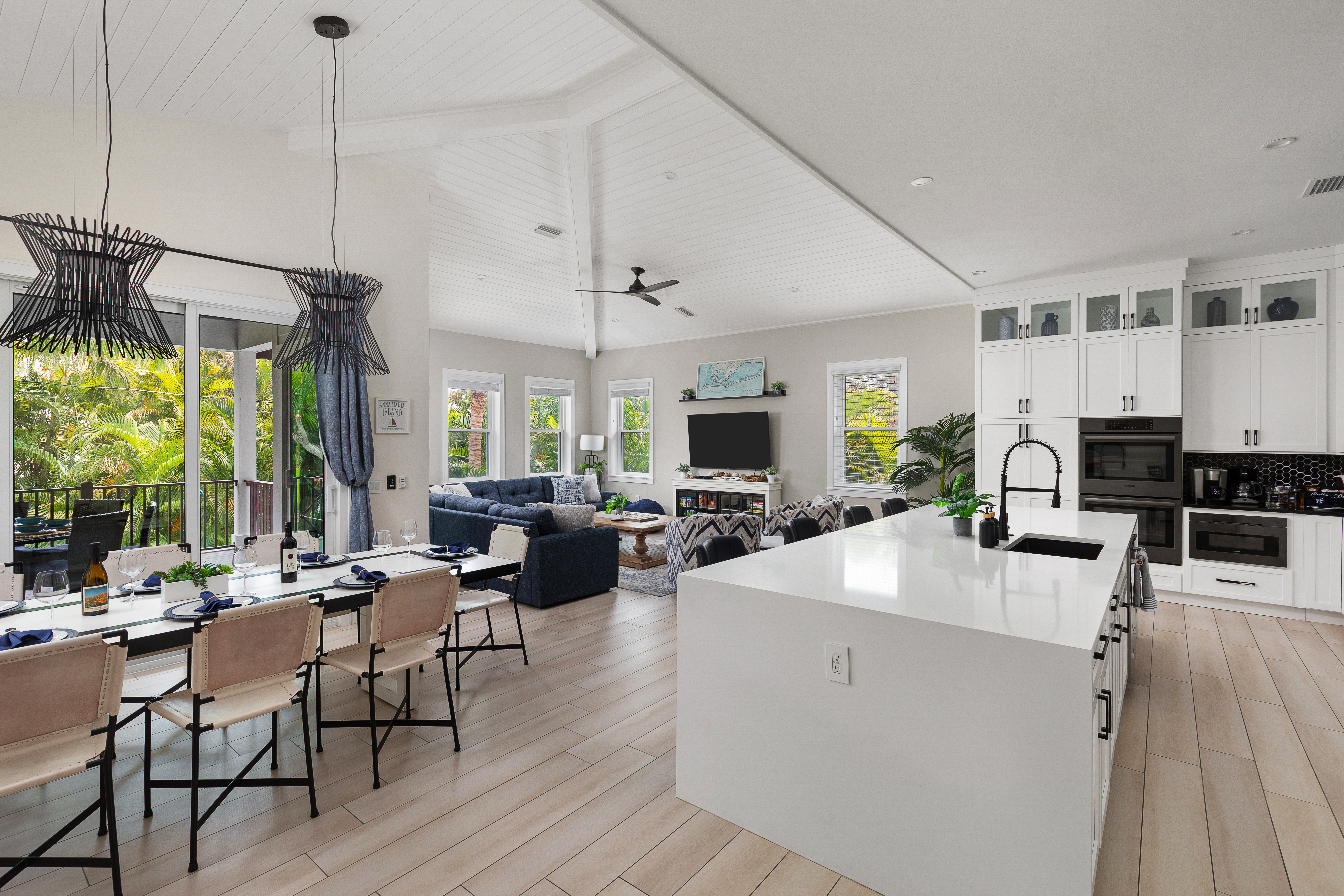 Open living, dining and kitchen with island seating and tropical views