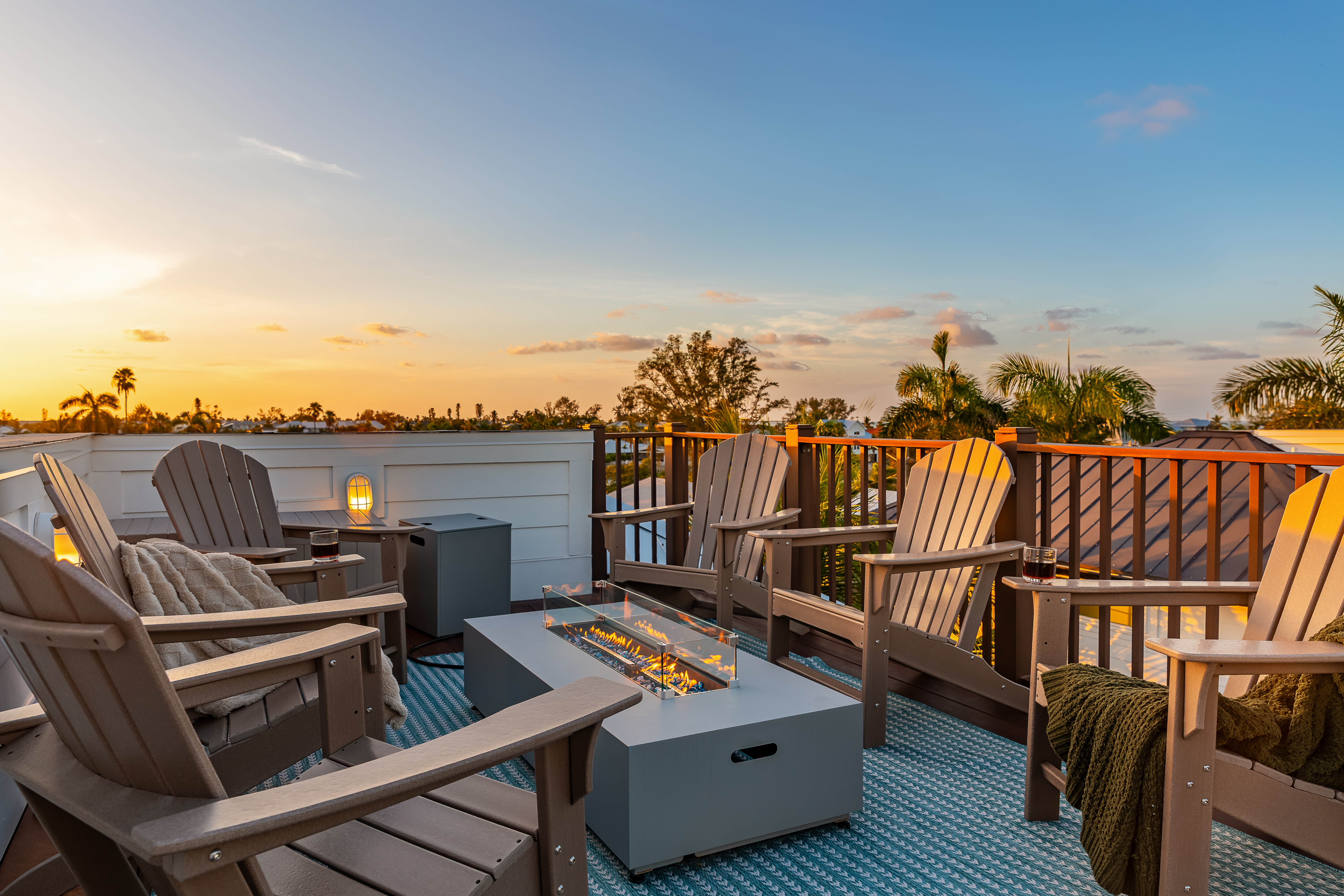 Rooftop fire table ringed with Adirondack chairs at sunset