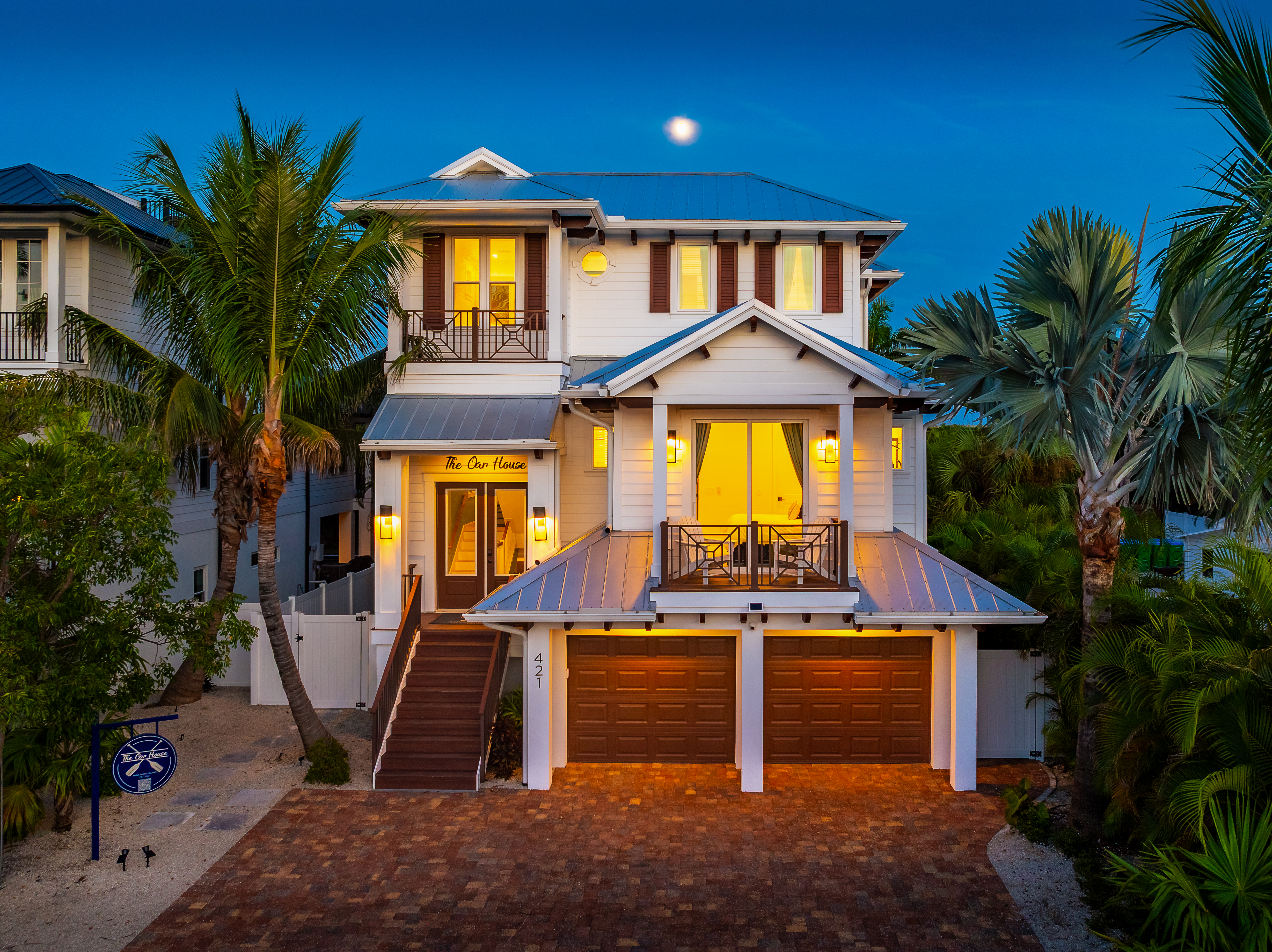 The Oar House at twilight, three stories on Pine Avenue with lit balconies and palms