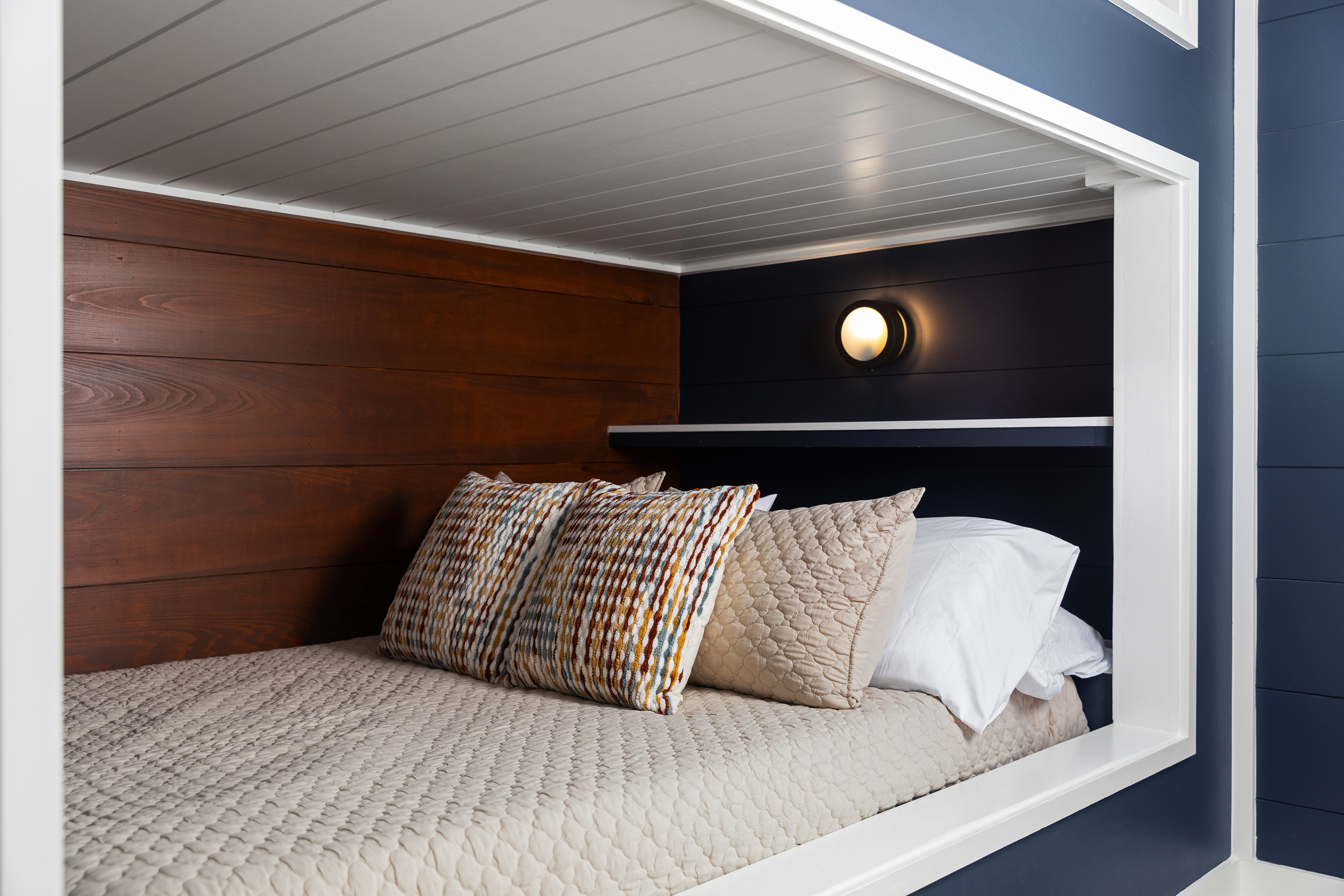 Full-size built-in bunk with wood accents and a reading light