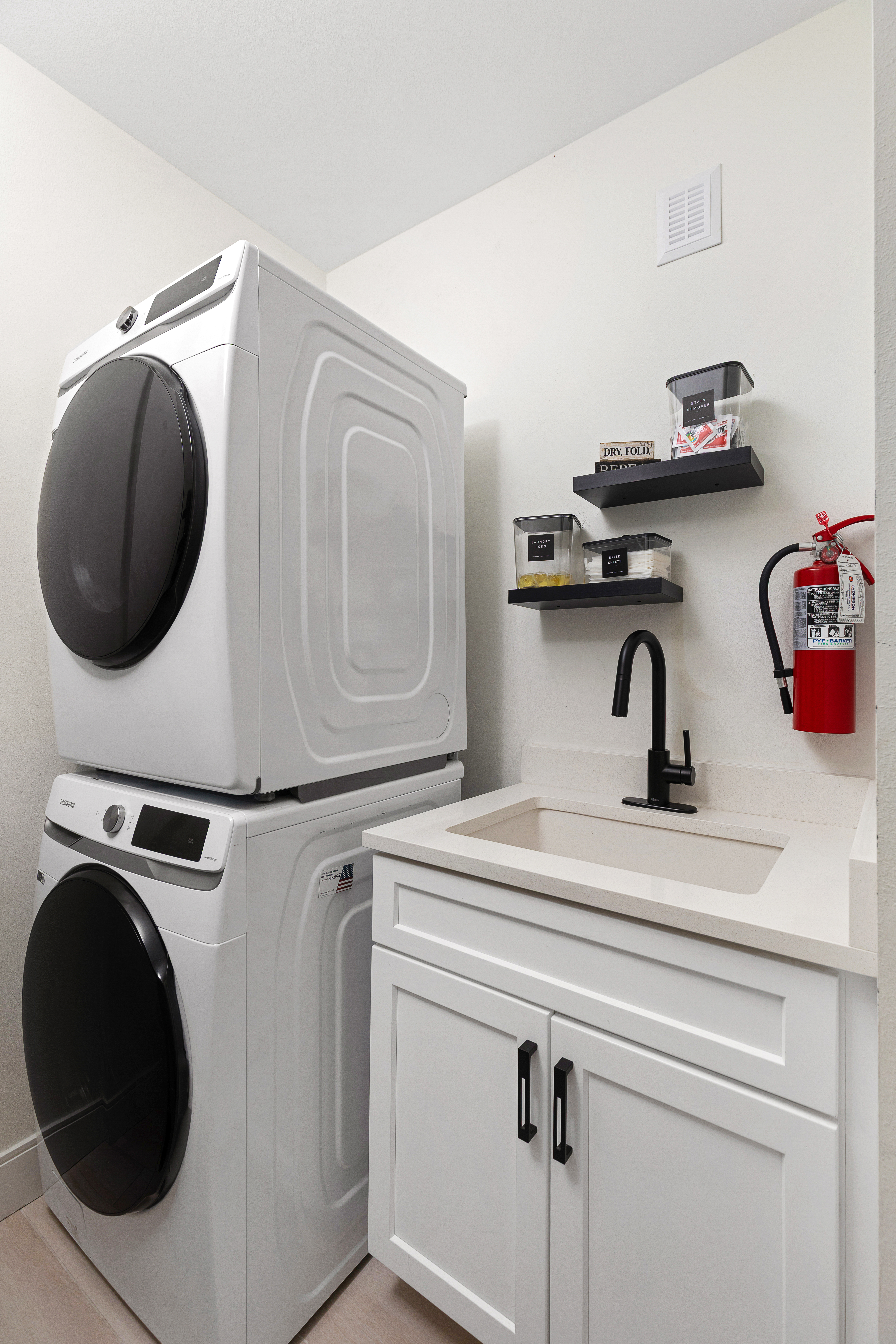 Laundry room with high-efficiency washer and dryer, deep sink and stocked supplies