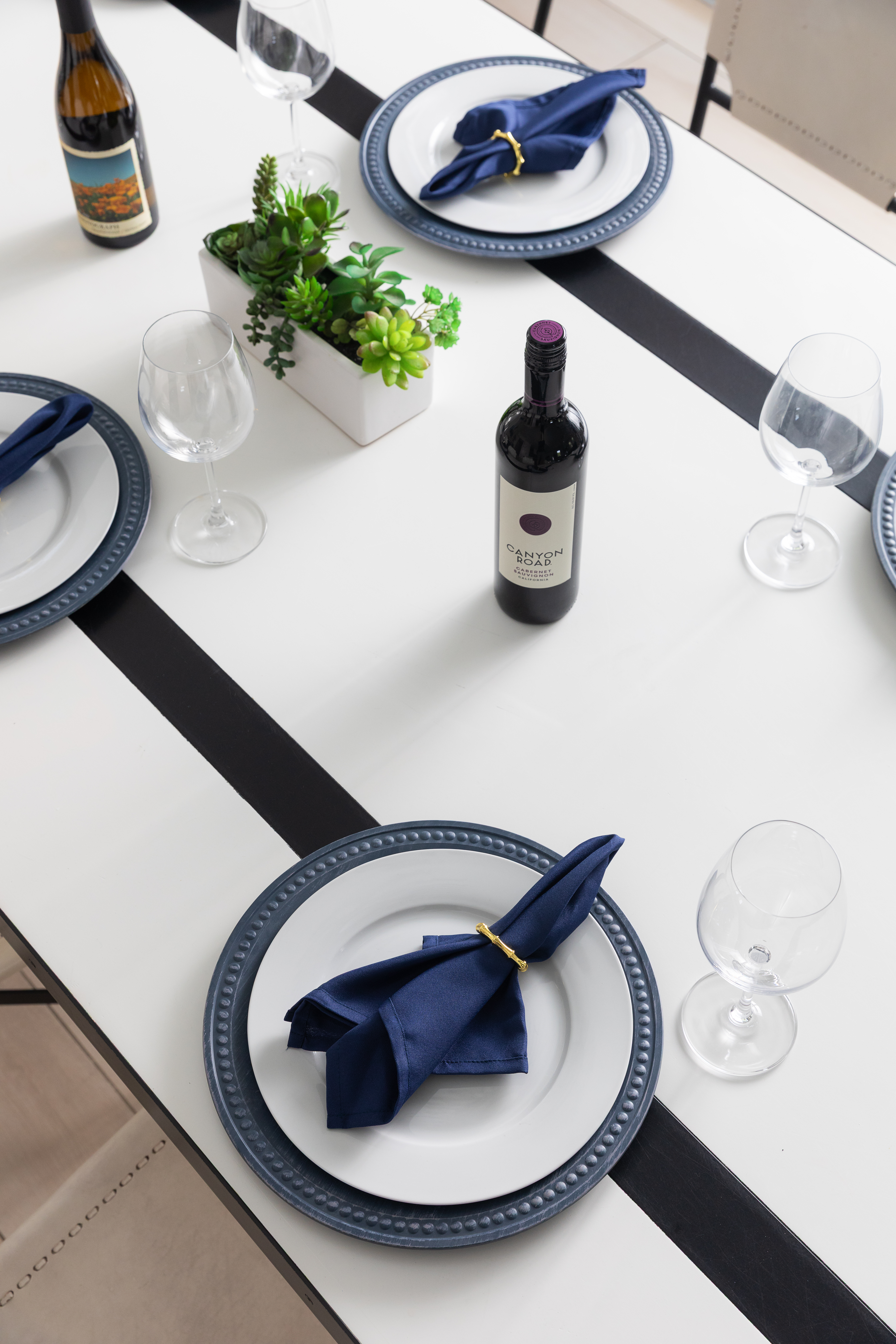 Dining table set with navy accents and two welcome bottles of wine