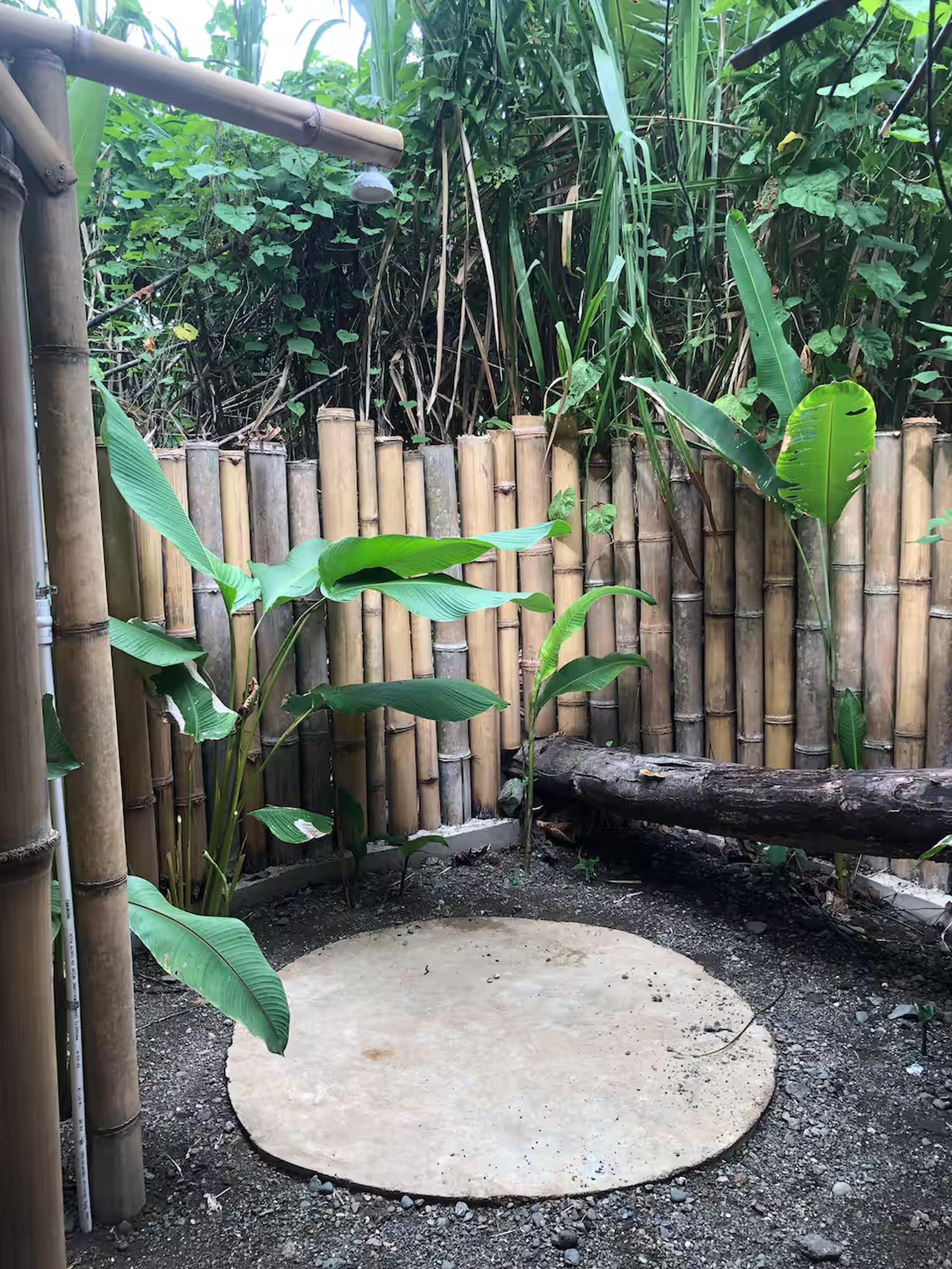 Private open-air bamboo shower surrounded by lush tropical greenery