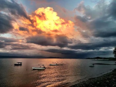 Stunning sunset waterfront views with calm boats and dramatic skies
