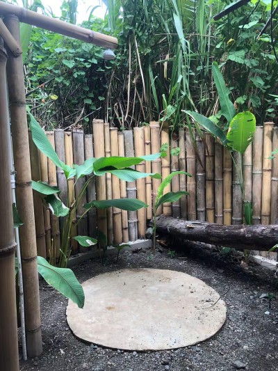 Private open-air bamboo shower surrounded by lush tropical greenery