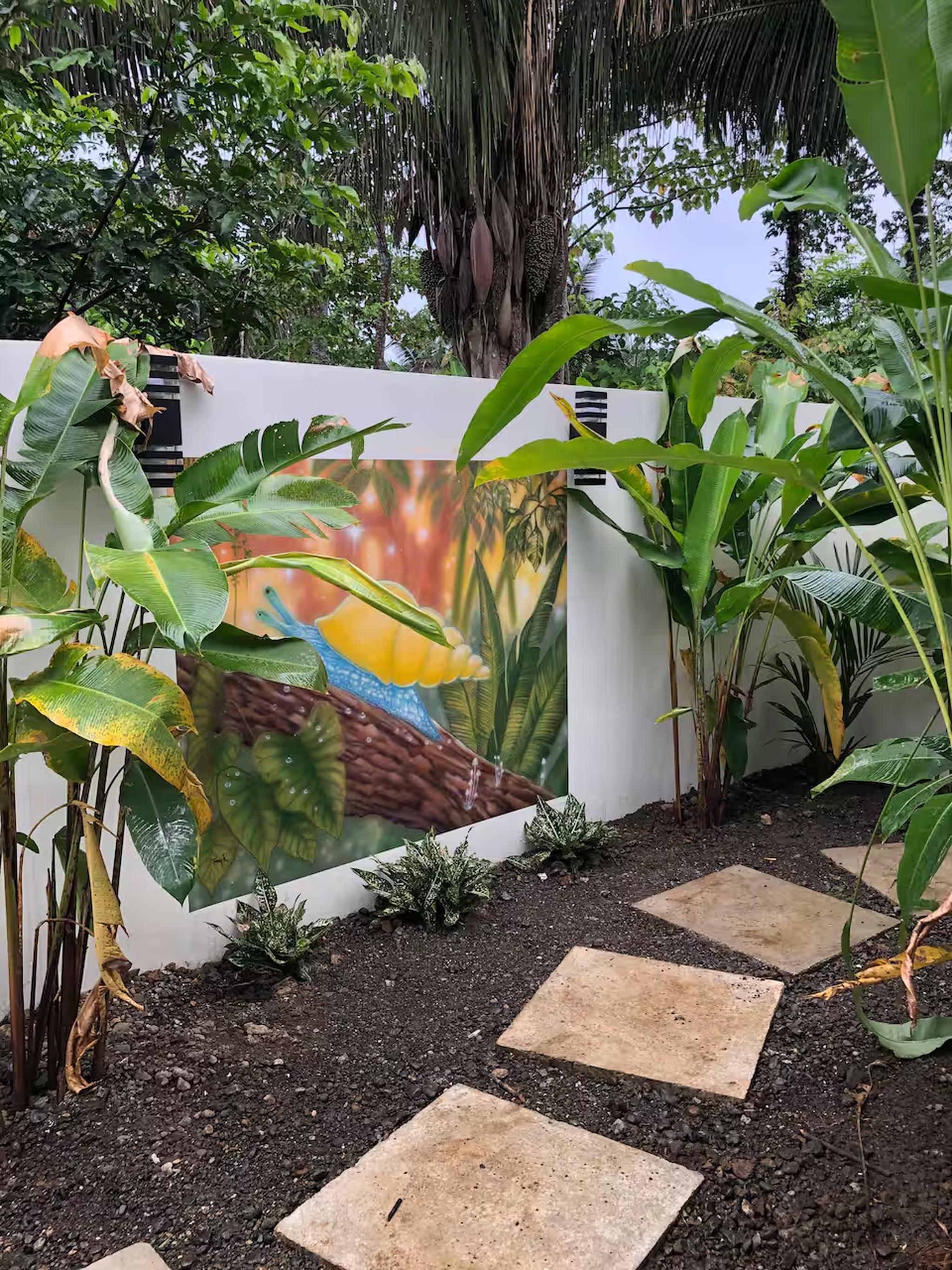 Private tropical garden path with vibrant mural and lush greenery