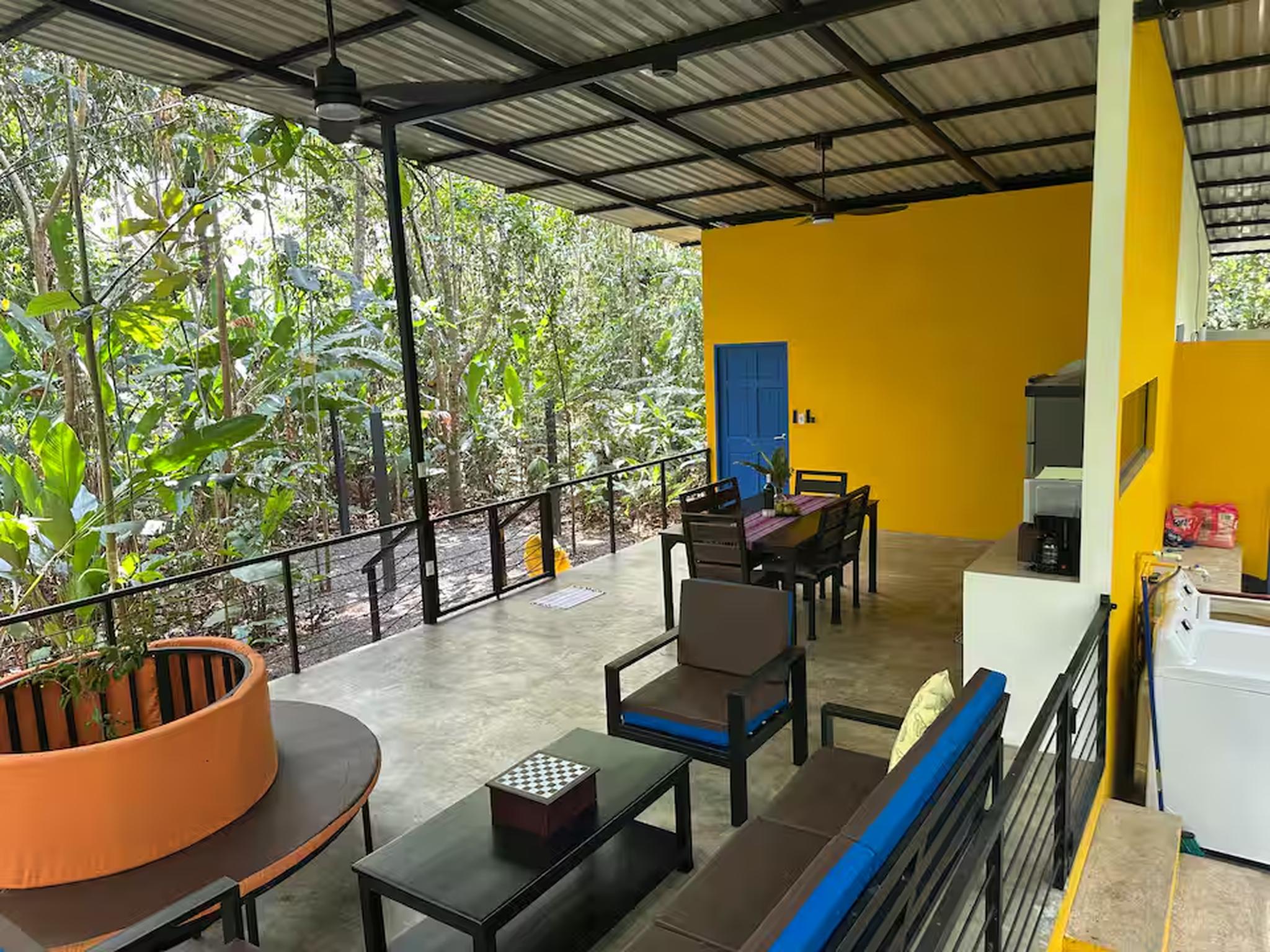 Covered jungle-view terrace with lounge seating, dining area, and kitchenette