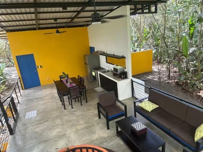 Covered jungle-view patio with outdoor kitchen, dining, and lounge seating