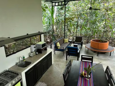 Open-air jungle lounge with dining, kitchenette, and cozy seating