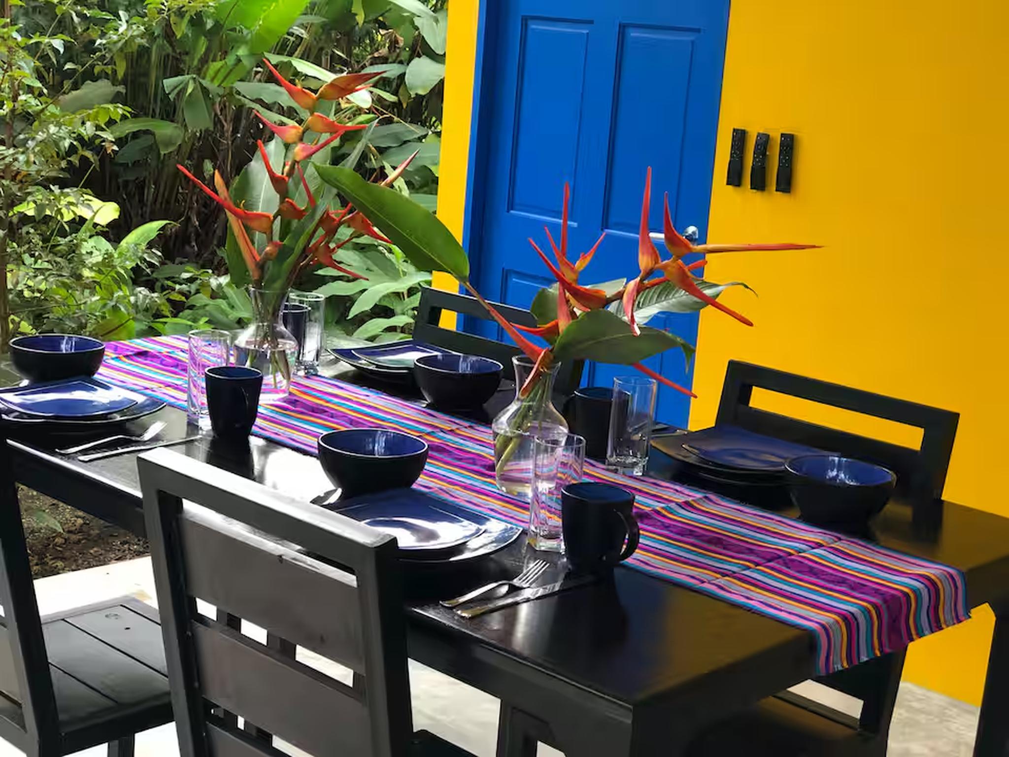 Colorful tropical outdoor dining space surrounded by lush greenery
