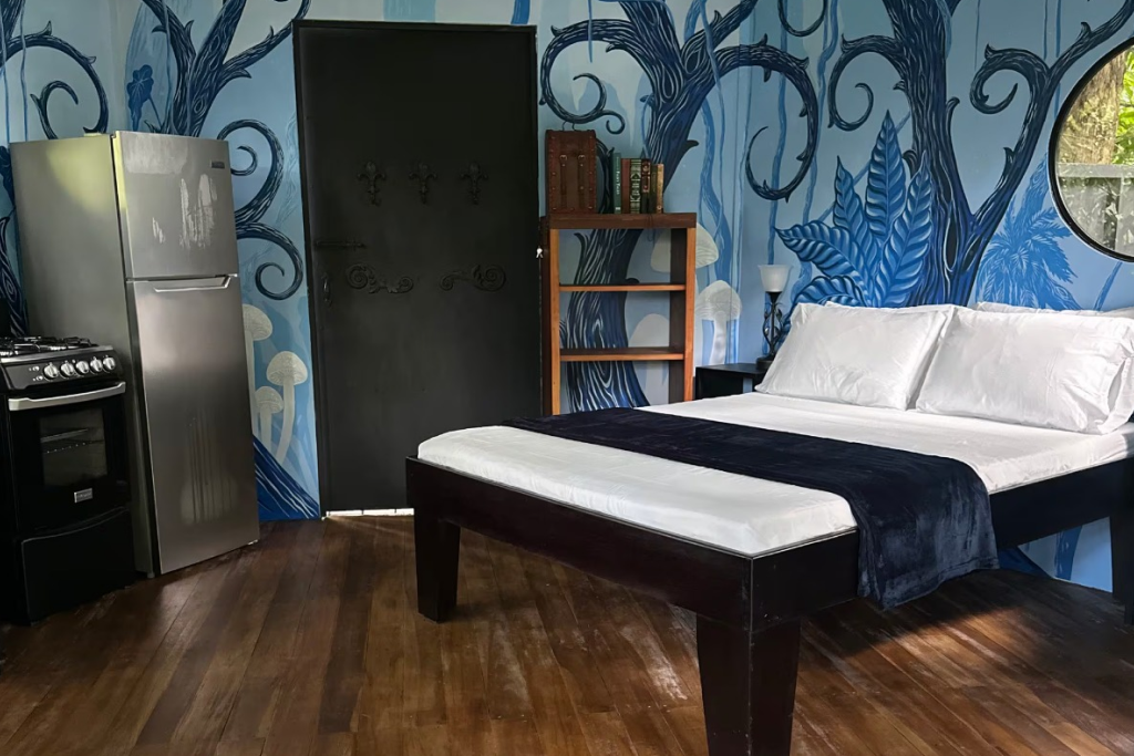 Artful studio with bold mural, cozy bed, and convenient kitchenette