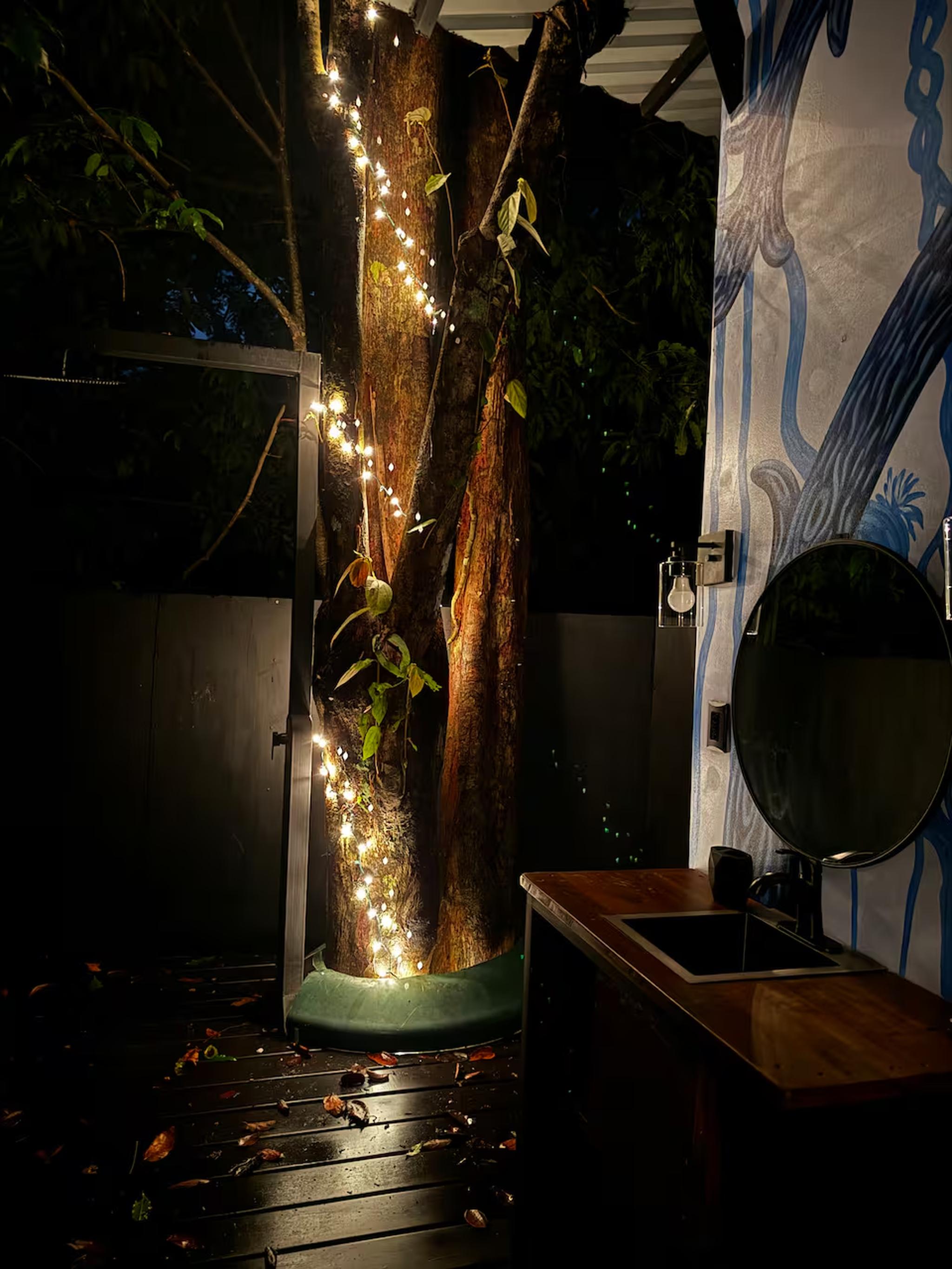 Open-air vanity with glowing tree lights and a chic tropical feel