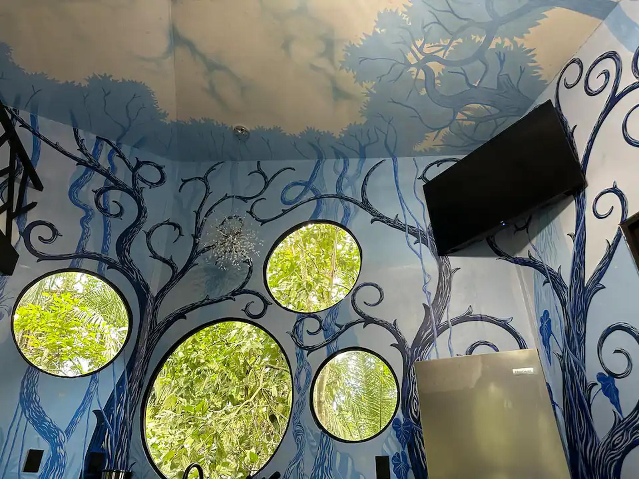 Whimsical mural room with round windows and lush tropical views