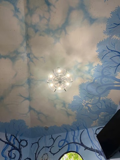 Whimsical mural ceiling with chandelier in a one-of-a-kind designer space