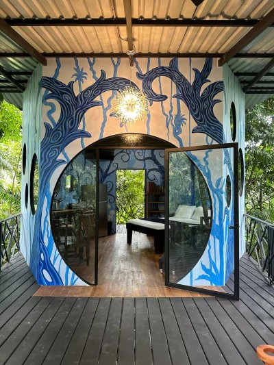 Art-filled jungle retreat with glass doors, deck, and serene nature views