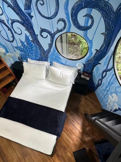Whimsical mural bedroom with round windows and treehouse-style charm